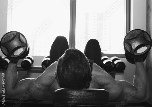 Fototapeta Naklejka Na Ścianę i Meble -  a man with big muscles is engaged in weightlifting in the gym. A pumped-up athlete goes in for sports on heavy weight simulators. sport exercises