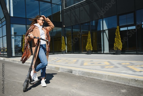 Young beautiful woman riding an electric scooter to work, modern girl, new generation, electric transport, ecology, ecological transport, sunset