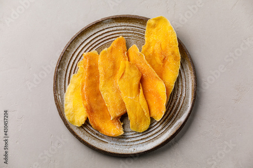 Fotografie Dried dehydrated Mangoes on plate on gray concrete background