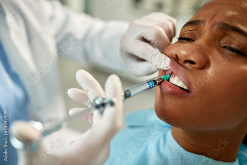 Close-up of African American woman receiving anesthetic during dental procedure.