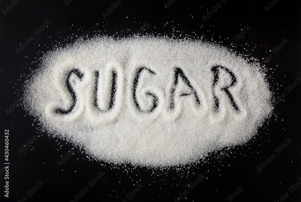 Heap of granulated white sugar on black background