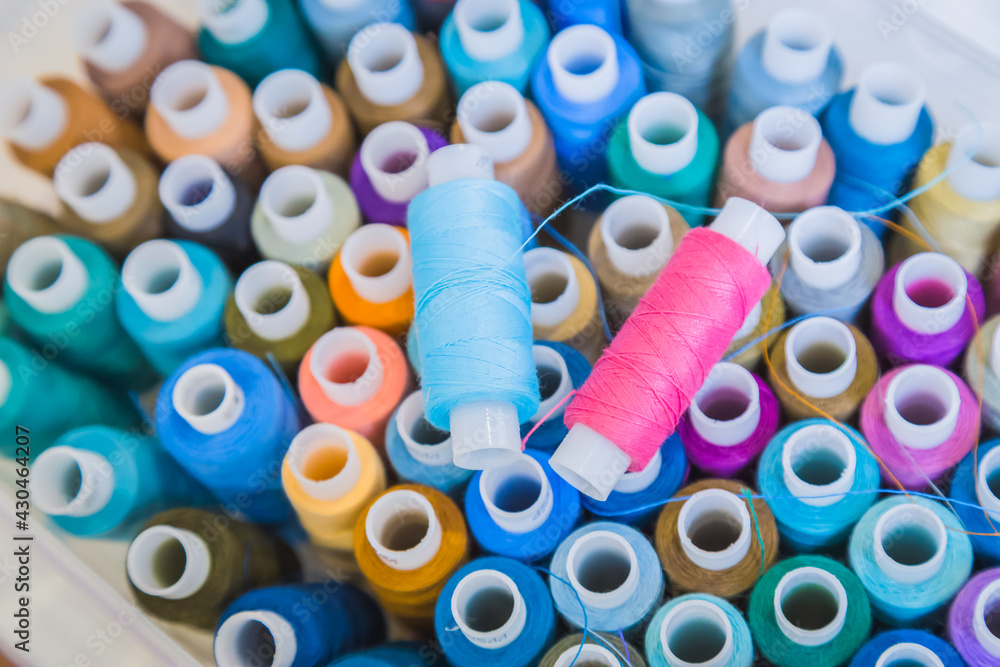Plastic bobbins, spools with colored thread on table at atelier - close up top view. Fashion, equipment for sewing, needlework, tailoring, hobby, clothing repair and dressmaking concept Plastic bobbins, spools with colored thread on table at atelier - close up top view. Fashion, equipment for sewing, needlework, tailoring, hobby, clothing repair and dressmaking concept