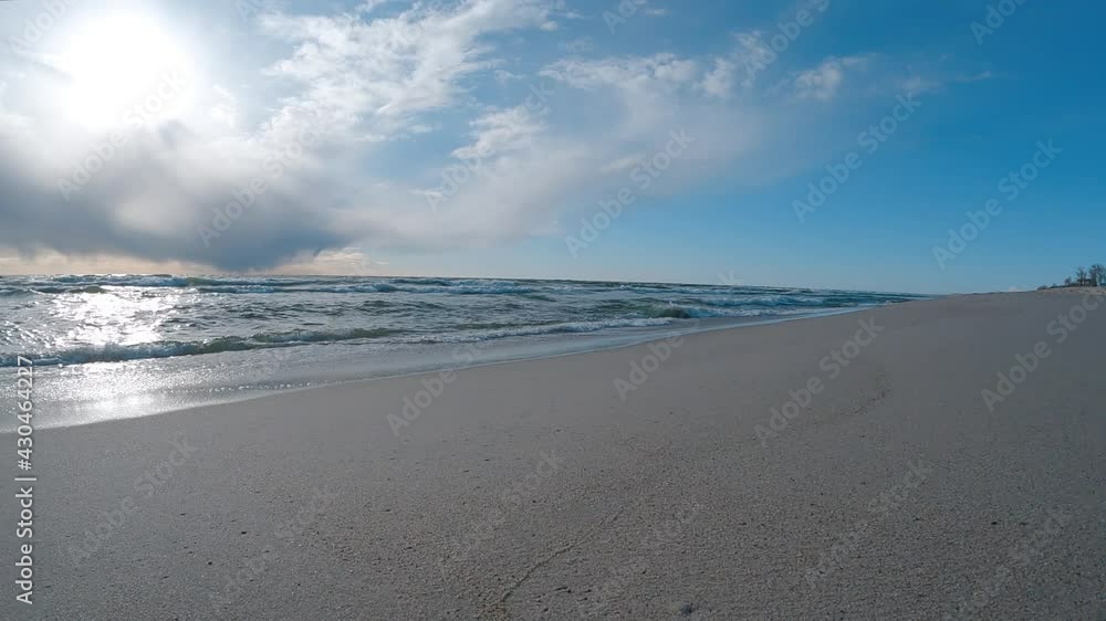 The cold Baltic Sea. Evening, sunset. Storm clouds. Waves wash over the sandy beach. Foam waves. Slow mo The cold Baltic Sea. Evening, sunset. Storm clouds. Waves wash over the sandy beach. Foam waves. Slow mo