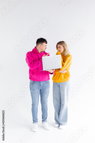 Photo of upset students man and woman 16-18 using silver laptop isolated over white background © ALEXSTUDIO