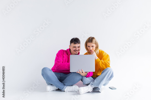 Pretty portrait of couple with laptop. sitting down. gray background