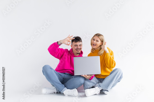 Pretty portrait of couple with laptop. sitting down. gray background