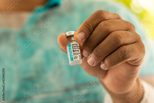 Mão de um enfermeiro mostrando ampola contendo a vacina contra covid-19. photo