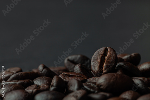 Roasted coffee beans on the old dark wooden background for wallpaper or decor. Shallow depth of field. Selected focuse