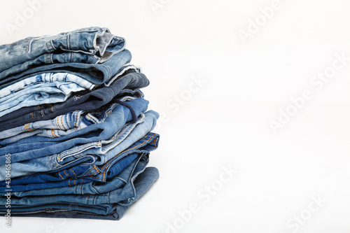 Stack of old blue jeans, cut pieces ready for recycling and scissors on white background. Circular economy. Pile of discarded old blue jeans. Zero waste Upcycle old denim garbage. Recycling old jeans.