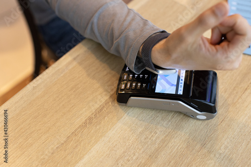 Unrecognizable man making wireless or contactless payment using smartwatch over nfc technology, apply to payment terminal. Concept e-commerce, people using contact less technology, business, cashless