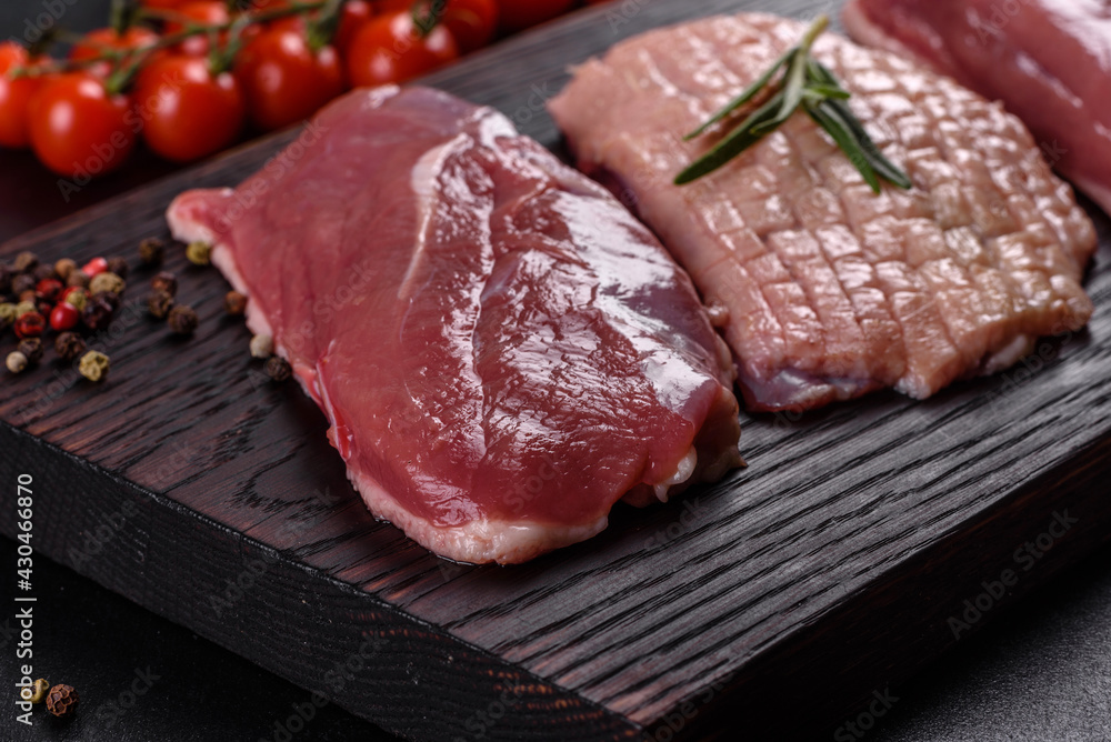 Raw duck breast with herbs and spices on a dark concrete background