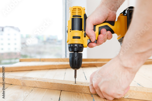 Handyman in blue uniform works with electricity automatic screwdriver. House renovation conception.