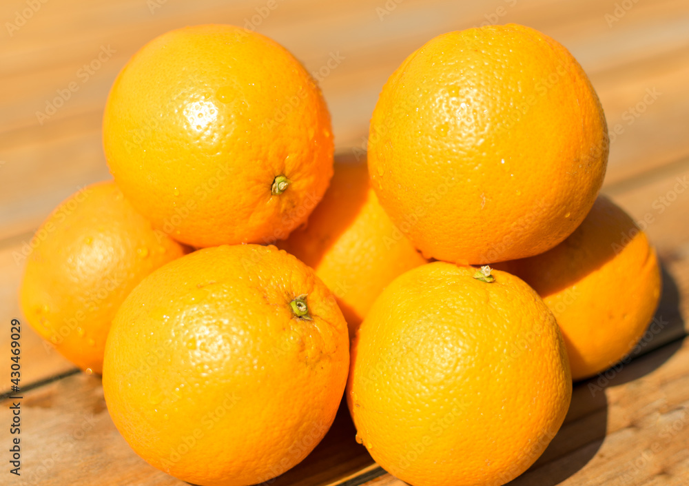 Oranges à presser humides exposées au soleil sur une table en bois Oranges à presser humides exposées au soleil sur une table en bois