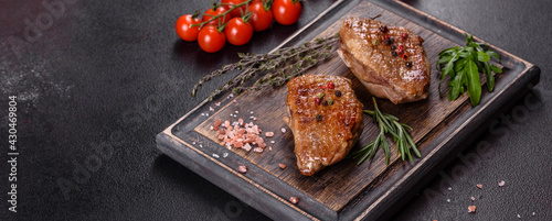 Baked duck breast with herbs and spices on a dark concrete background