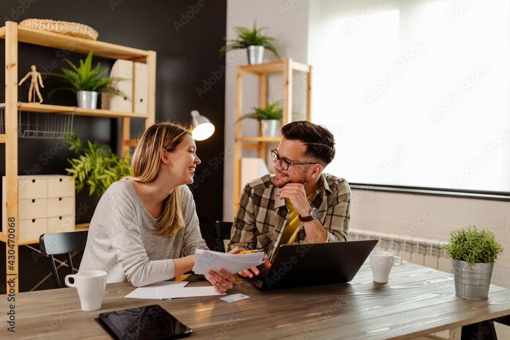Fototapeta premium Happy young married couple sit on the table, calculate expenses use easy online banking service.
