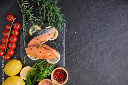 Fresh fish. piece of raw salmon fish fillet, spices on a black stone surface, Delicious fish meat. top view. Healthy food.