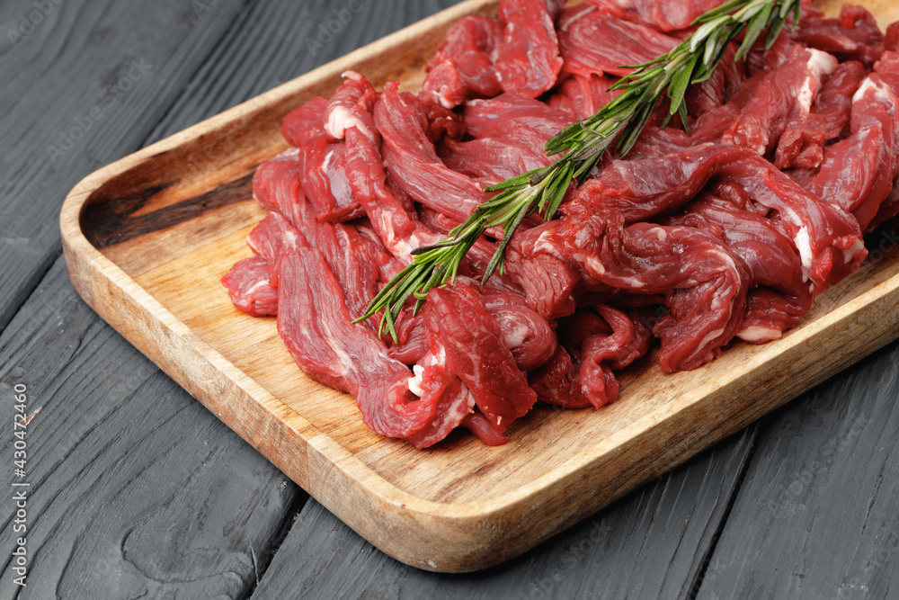 Raw sliced beef meat on wooden board Raw sliced beef meat on wooden board