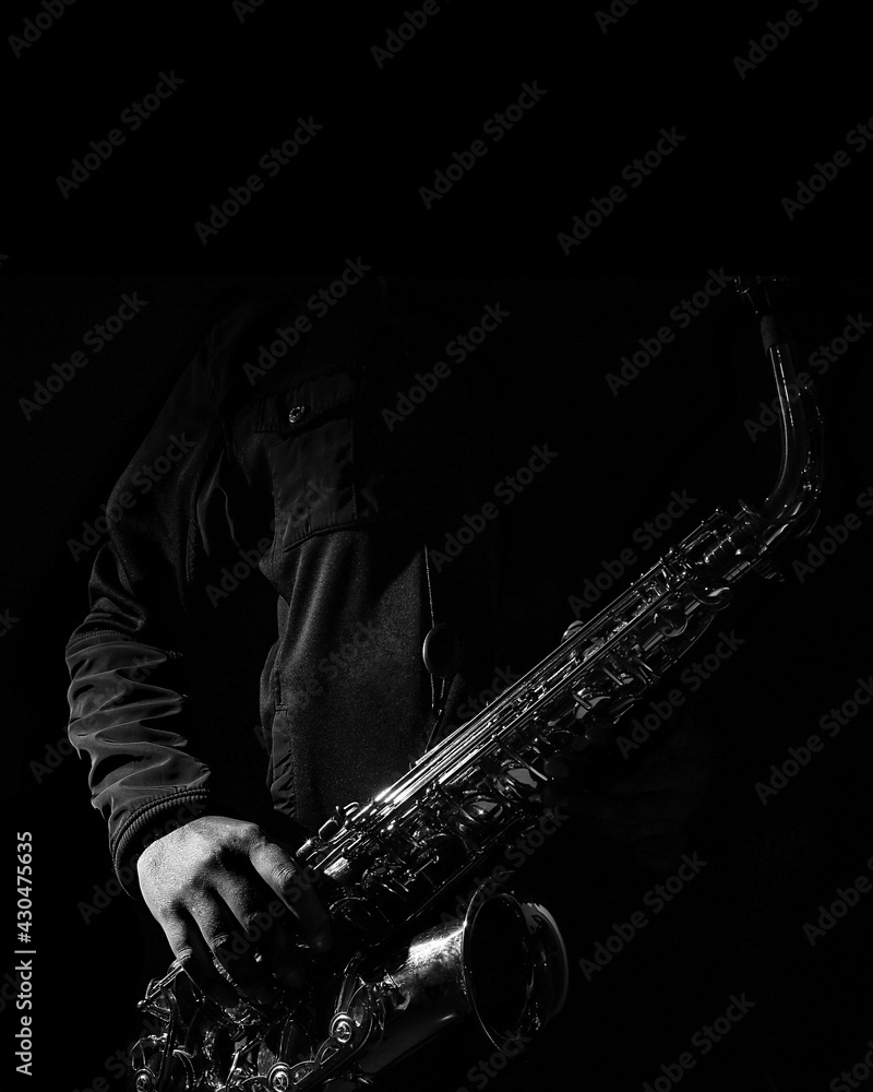 Foto de fotografía de stock de un saxofonista con abrigo negro posando con  su saxofón para portada do Stock | Adobe Stock