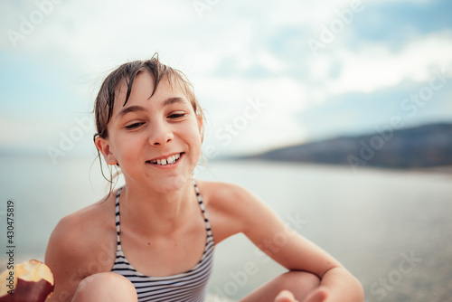 Girl eating apple at the beach and laughing
