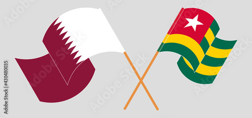 Crossed and waving flags of Qatar and Togo
