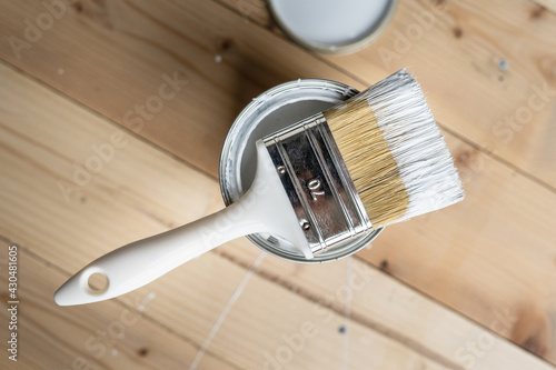 Top view on white paint brush on the opened can on the wooden table or floor painting and renovation repairing concept photo