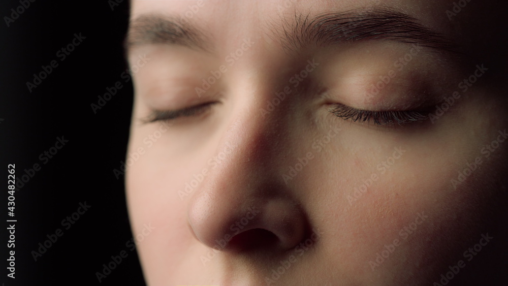 Macro of female face beauty resting with closed eyes in black studio.Tired woman Macro of female face beauty resting with closed eyes in black studio.Tired woman