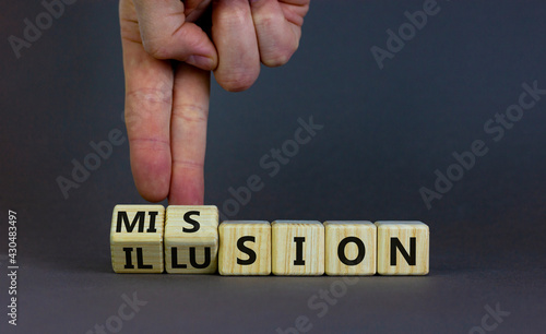 Mission or illusion symbol. Businessman turns wooden cubes and changes the word 'mission' to 'illusion'. Beautiful grey table, grey background, copy space. Business and mission or illusion concept.