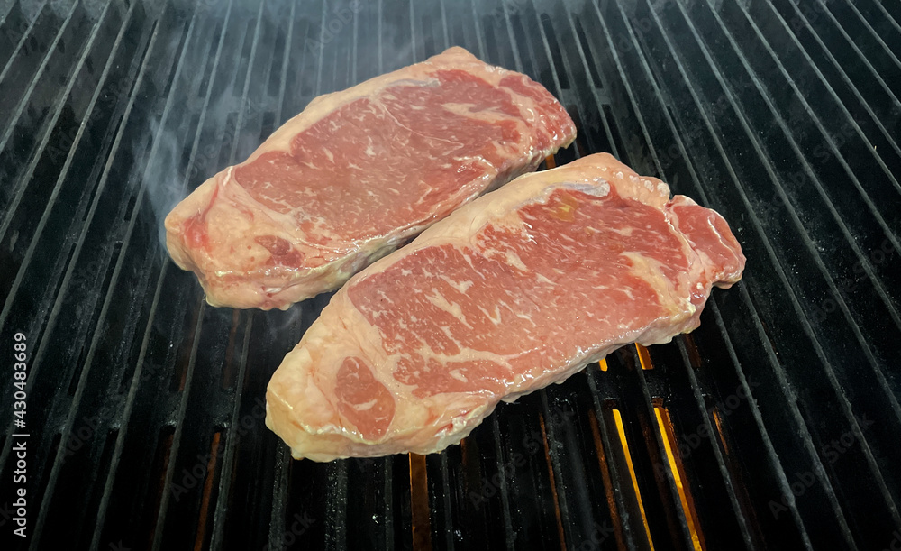 rib-eye steaks cooking on flaming grill .
