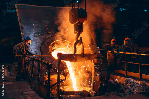 Fototapete Pouring bright liquid iron or metal with sparks into container in steel mill or workshop blast furnace foundry