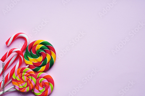 Colorful lollipops in sugar canes on a stick on a pink background. Flat lay, copy space