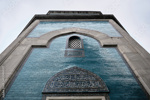 29.03.2021. Bursa Turkey. Green tomb (Yesil Turbe) with iznik pottery (cini) or tiles covered tomb wall. Arabic letters above the windows and green tiles extends to rainy and overcast sky in Bursa.