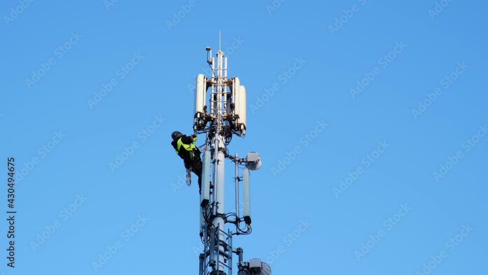 Telecommunication Technician Working at Height Fixes Transmitter Relay Microwave Antenna on Top of Radio Tower Telecommunication Technician Working at Height Fixes Transmitter Relay Microwave Antenna on Top of Radio Tower