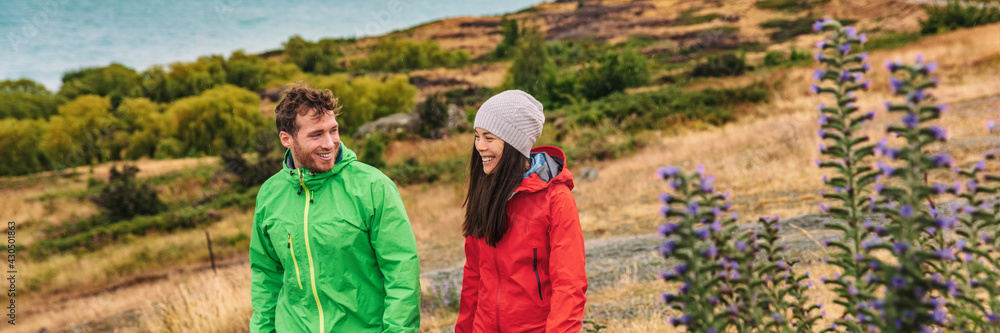 Fototapeta premium New Zealand travel - couple tourists hiking at nature view of Lake Pukaki near Aoraki aka Mount Cook, a famous travel road trip tourist destination. Panoramic banner of young couple hiking in nature