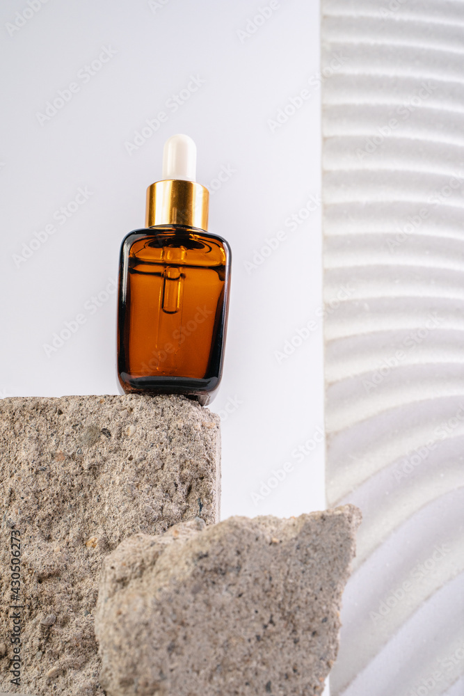 The bottle of Essence is on the pedistal. Lotion on a white background. Cosmetics for skin health. Aromo Oil. Serums with vitamin C. Unisex cosmetics. Mockup. 