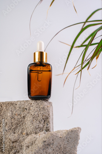 The bottle of Essence is on the pedistal. Lotion on a white background. Cosmetics for skin health. Aromo Oil. Serums with vitamin C. Unisex cosmetics. Mockup. 