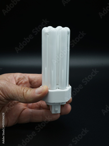 Man holding compact flourescent light bulb. Close-up. Isolated on black.