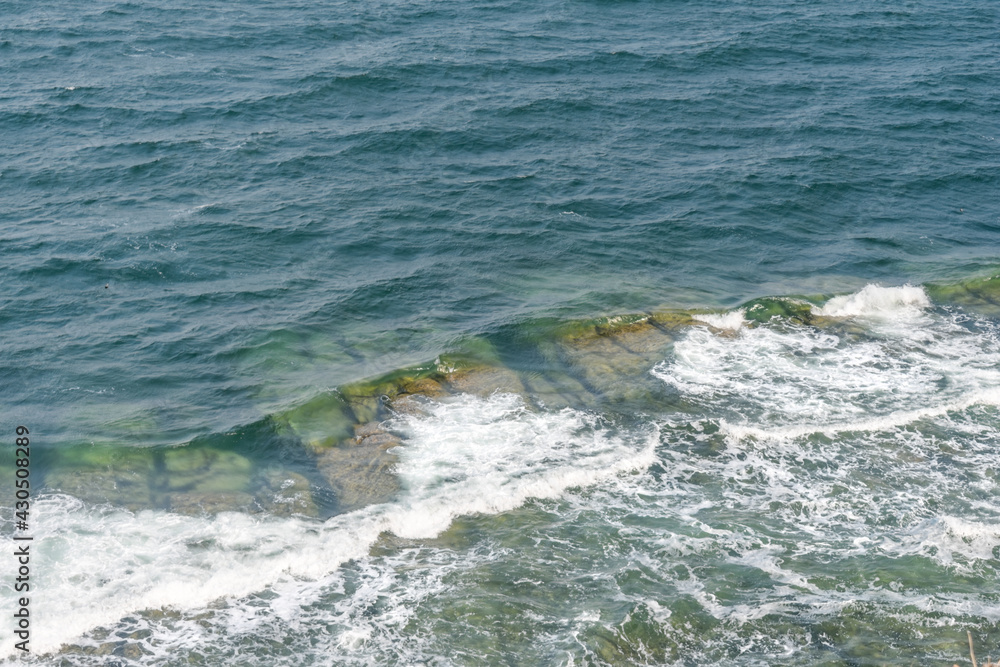 Sea waves crash against rocks and form foam