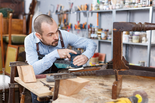 Professional carpenter engaged in restoring antique furniture using instruments