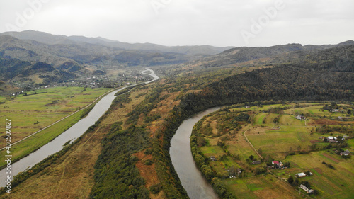 Aerial drone view of summer mountain meadow landscape with river and cloudy sky on background