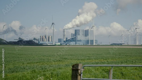 Eemshaven factory gas and coal power plant billowing smoke next to wind turbine farm