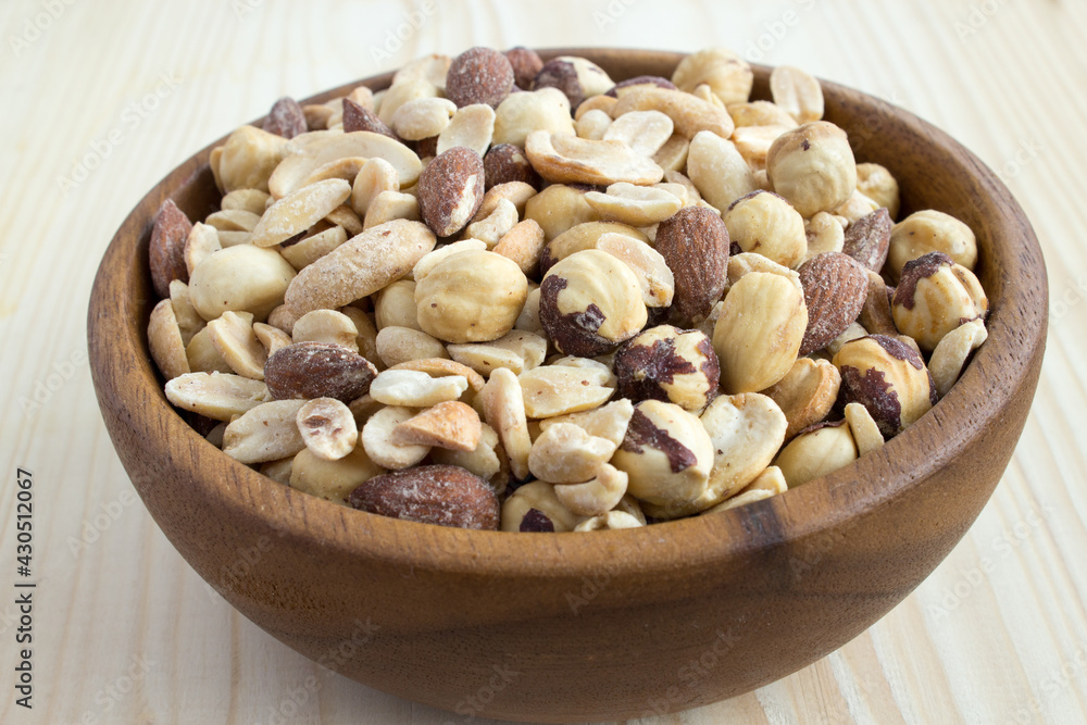Salted nuts. Salted nuts cocktail on a wooden background. Mix of nuts in a wooden bowl. Close-up. Salted nuts. Salted nuts cocktail on a wooden background. Mix of nuts in a wooden bowl. Close-up.