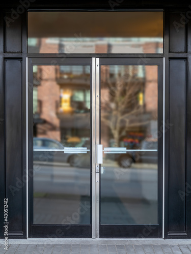 Photography Exterior building entrance with black steel double glass door and defocused reflection from traffic and neighboring building