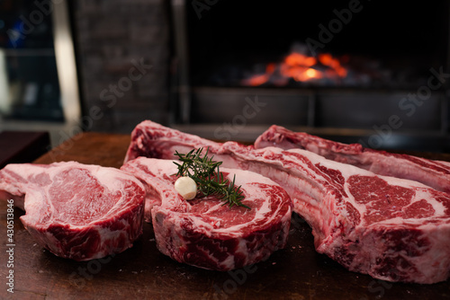 Tomahawk steak on a large wooden cutting board There was a backdrop of a bonfire in the grill.