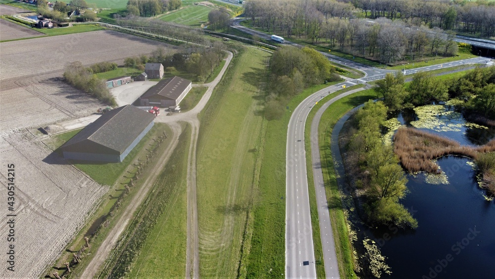 Farm situated on a road in green surroundings. Arable land that has been plowed to cultivate new crops. Aerial view made with drone.