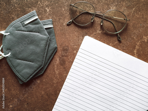 notebook with pen and glasses and mask