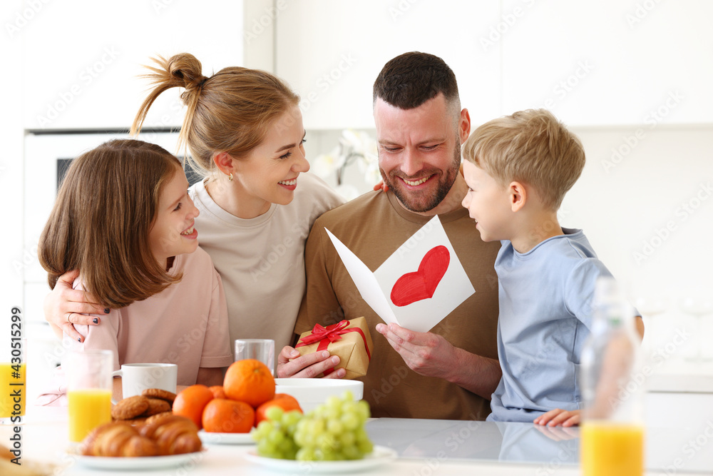 Mom with children congratulating dad with Fathers day while having breakfast in kitchen
