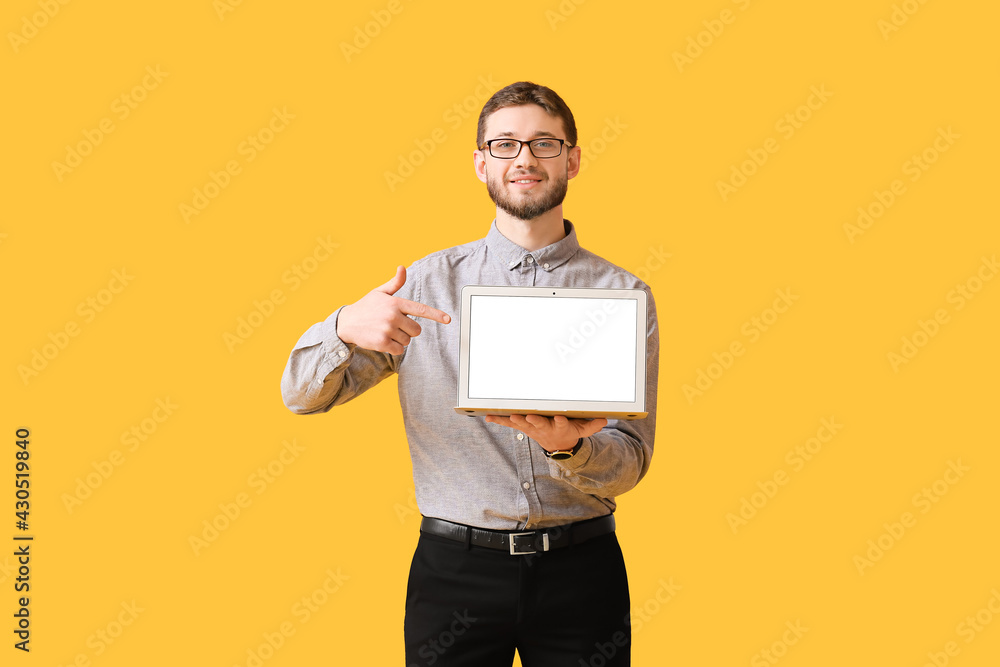Handsome man pointing at laptop on color background Handsome man pointing at laptop on color background