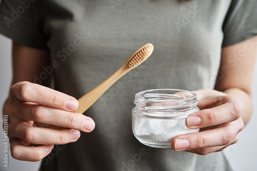 Woman holds bamboo toothbrush and soda powder in her hands