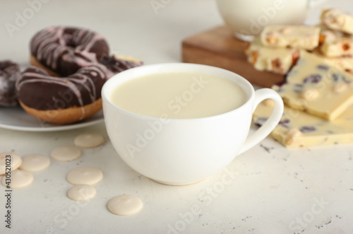 Cup with hot white chocolate on light background