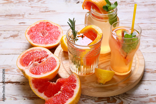 Glasses of tasty grapefruit lemonade on light wooden background
